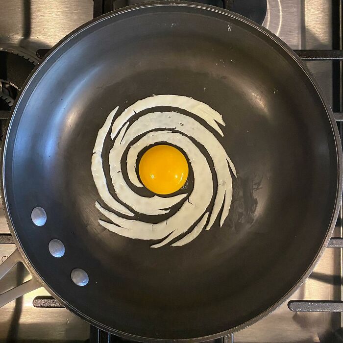 Creative fried egg art in a pan, with yolk and whites arranged in a spiral pattern.