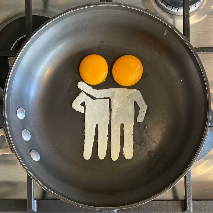 Creative fried eggs art depicting two figures with yolks for heads in a skillet.