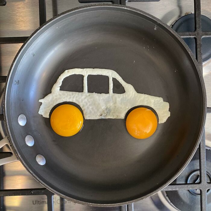 Fried egg shaped like a car in a pan, showcasing creative egg art by an artist.