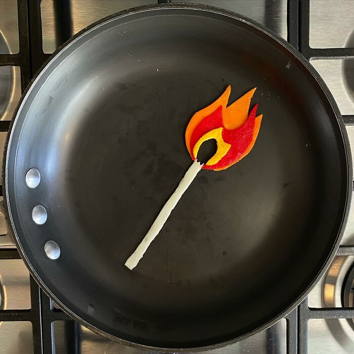 A creative egg art piece resembling a fiery matchstick in a frying pan.