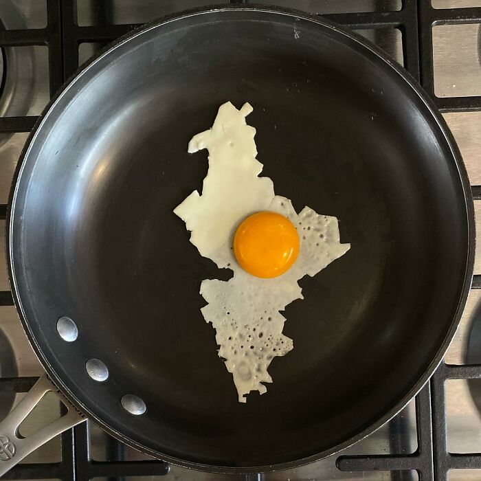 Creative fried egg art resembling a map in a frying pan.