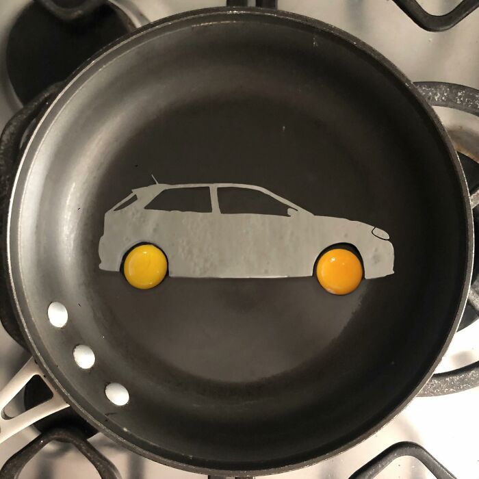 Creative egg art shaped like a car in a frying pan with yolk wheels.