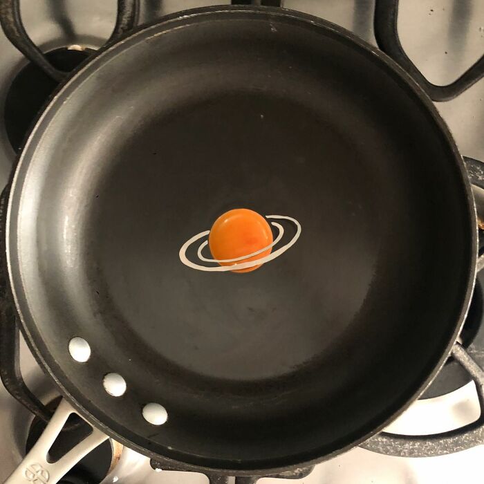 A creative fried egg design resembling a planet with rings in a frying pan, showcasing artistic cooking techniques.