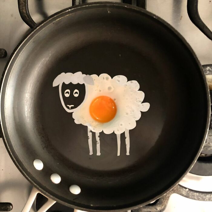 A creative egg art of a sheep in a frying pan.