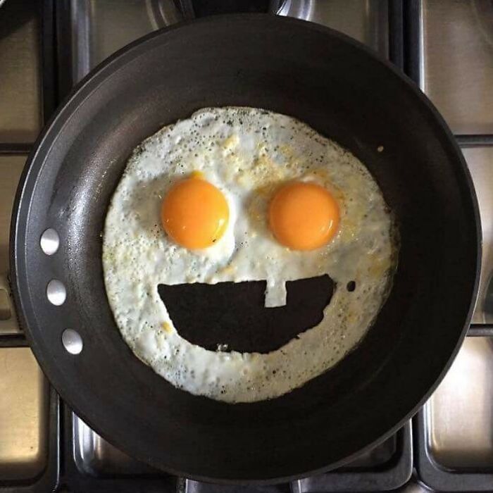 Creative fried eggs in a pan with yolks and a smiling face design.