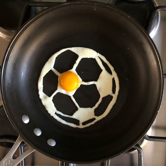 Creative fried egg resembling a soccer ball in a frying pan.