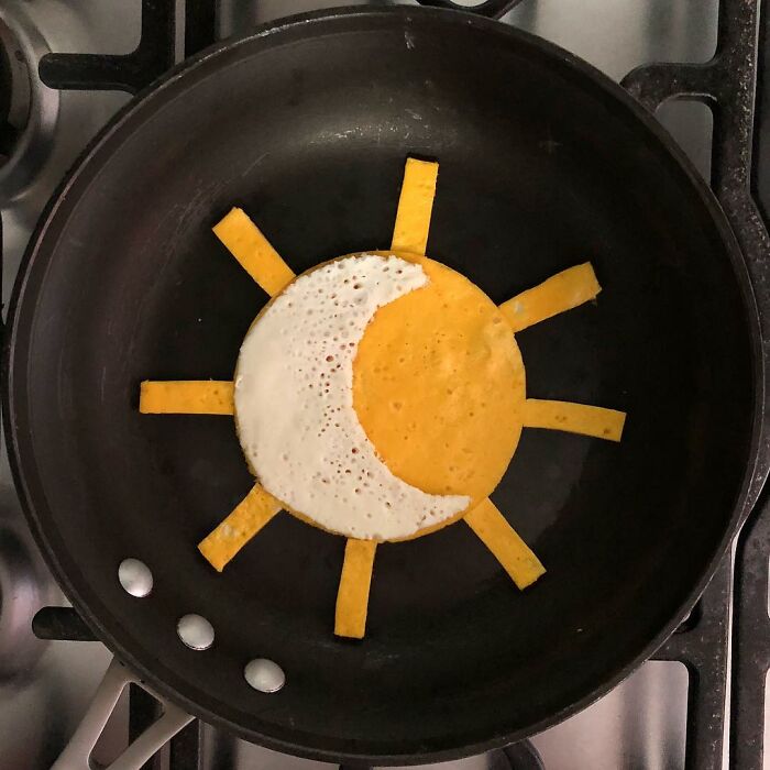 Creative fried egg art resembling a sun and moon in a black skillet.