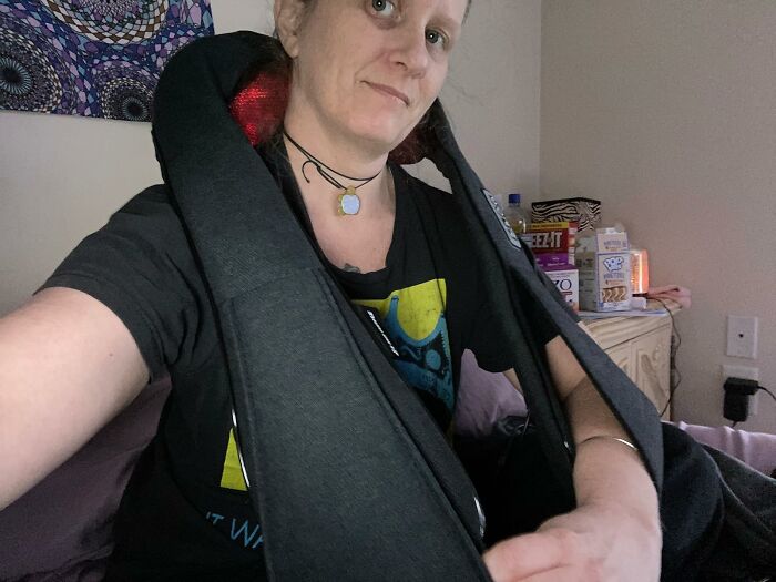 A woman using a neck massager, enjoying a relaxing moment at home.