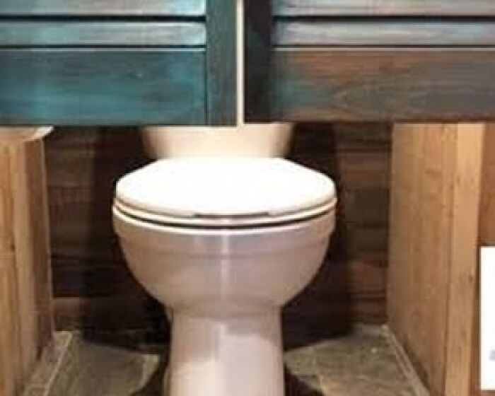 Construction fail: Cabinet awkwardly installed over toilet, blocking its use.