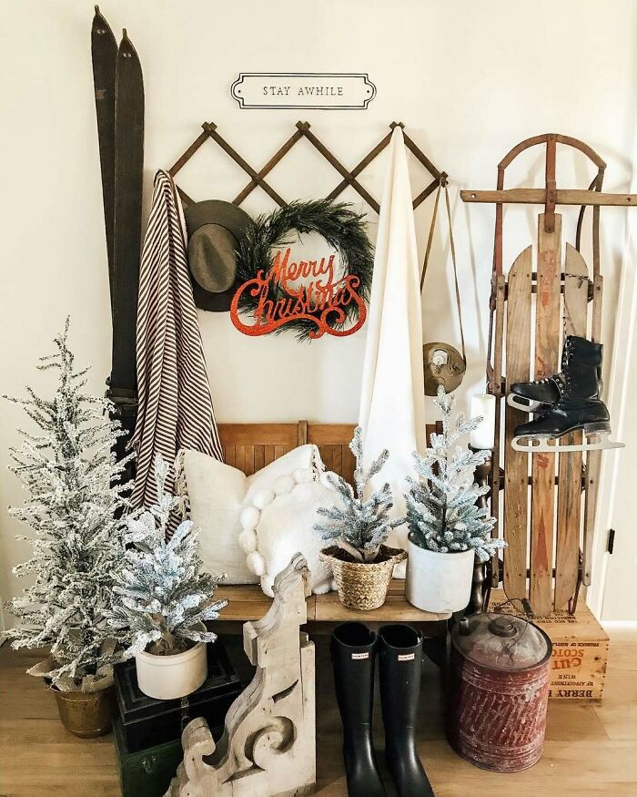 Cozy Christmas decorating ideas with frosted trees, rustic sled, and "Merry Christmas" wreath on a bench.