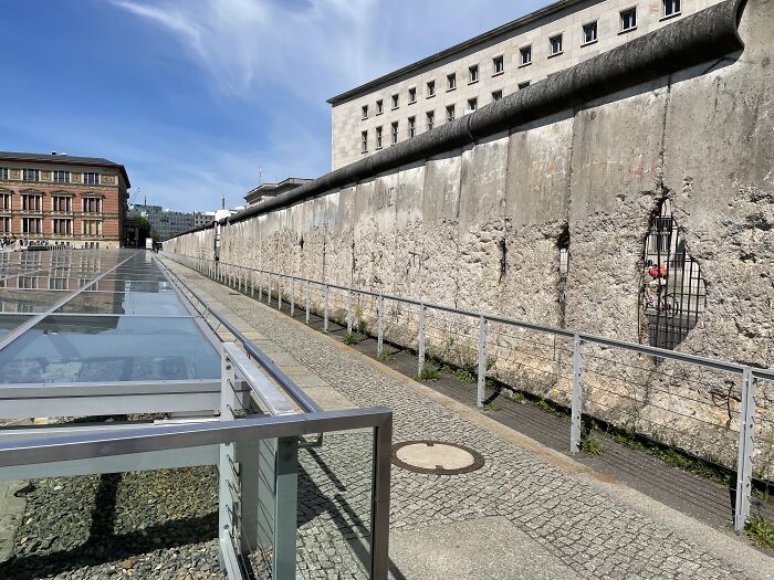 Historic Berlin Wall section under a clear sky, with nearby modern structures, symbolizing influence on history.