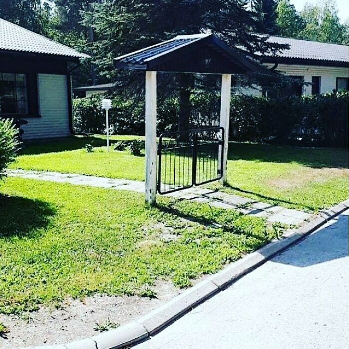 Construction fail with a freestanding gate and roof in a garden, no connecting fence visible.