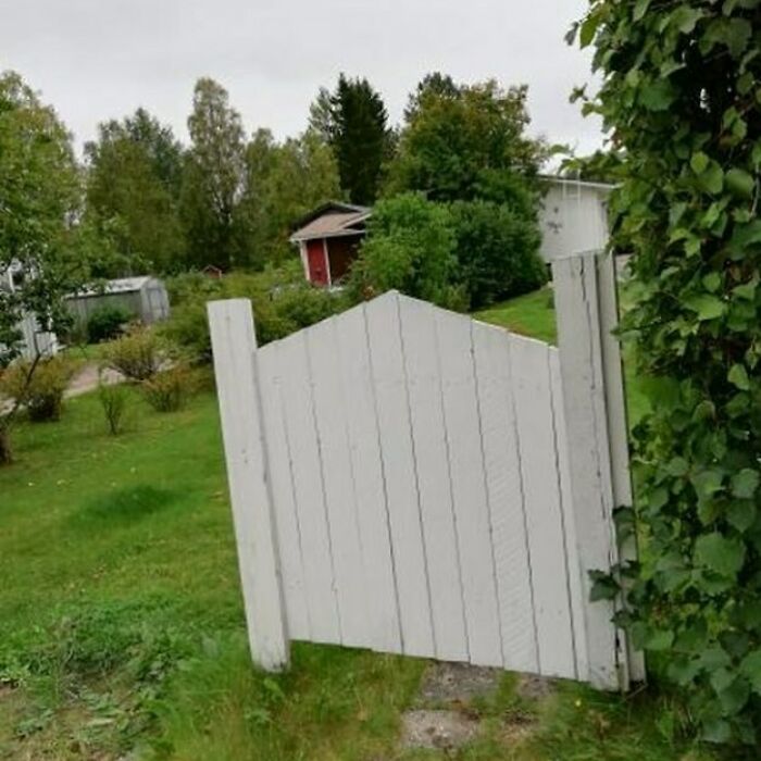 Misaligned garden gate showcasing a construction fail in a scenic backyard.