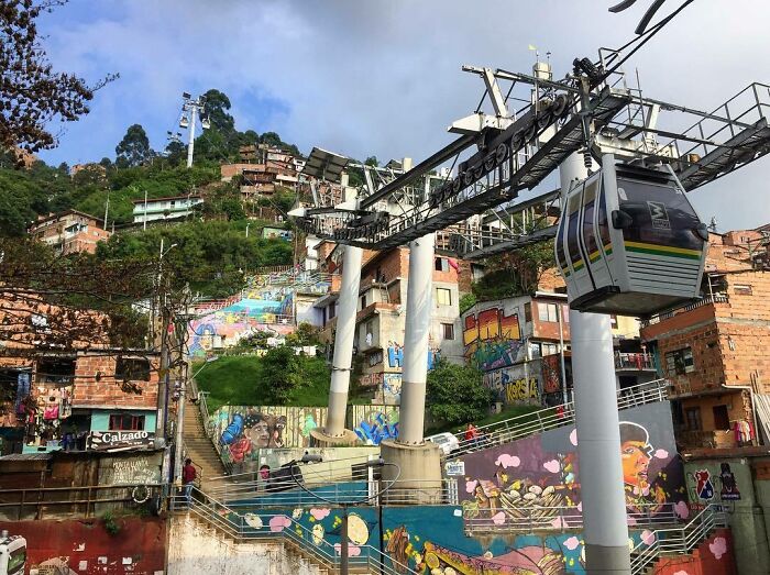 Cable car over a colorful urban hill with graffiti, resembling a scene from a video game.