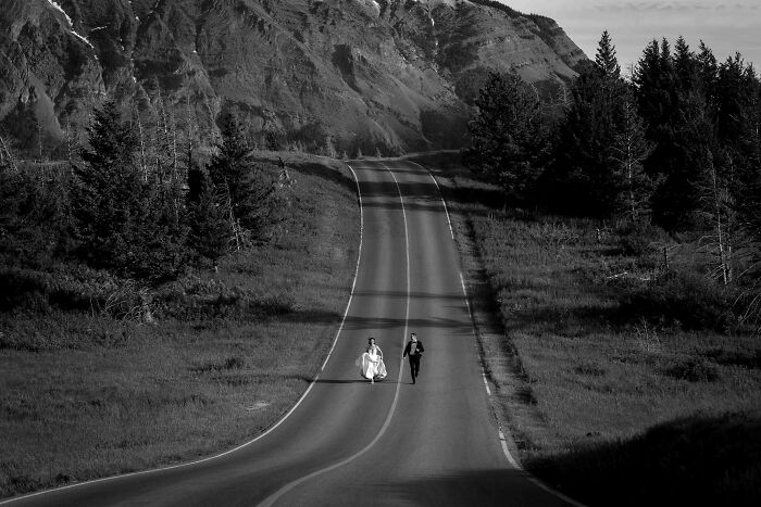 Bride and groom walking on a scenic road with mountains in the background, one of the top wedding photos of 2024.