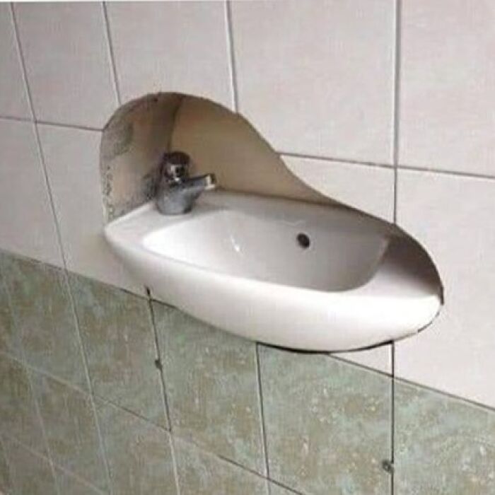 Bathroom sink poorly installed, cutting into wall tiles, showing a construction fail.