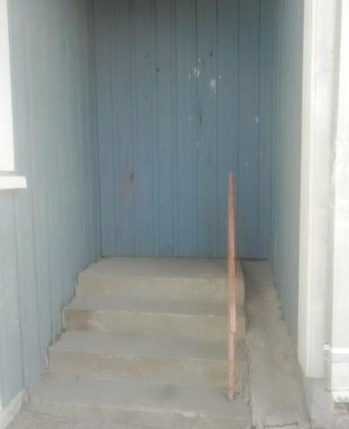 Construction fail: concrete steps leading directly into a solid wall, with a misplaced handrail.