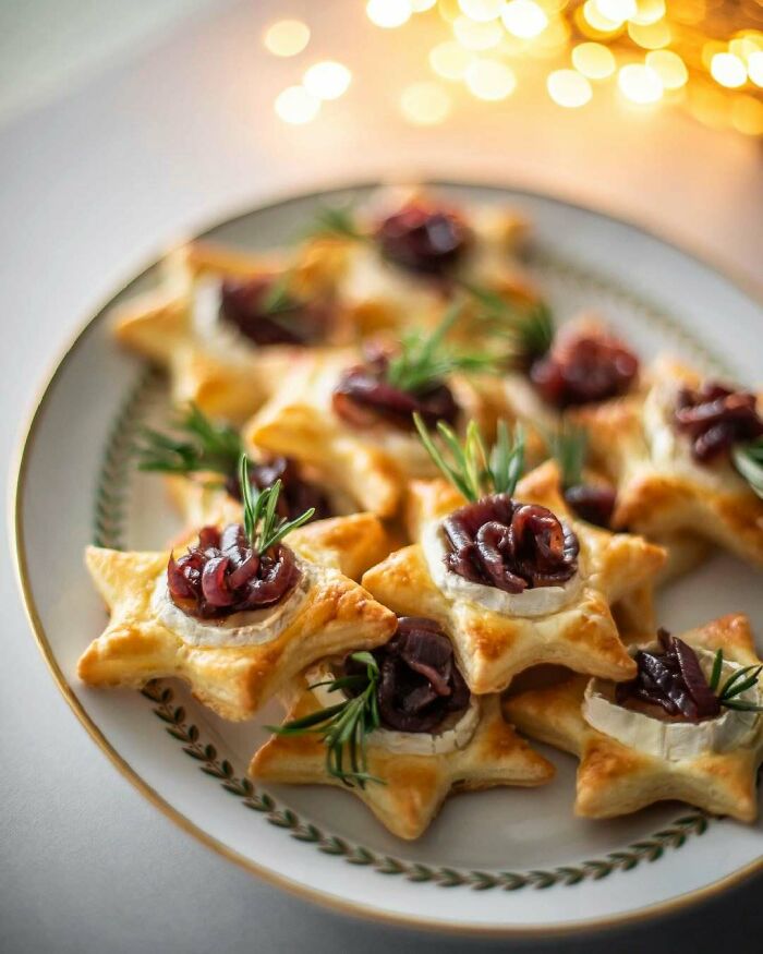 Star-shaped Christmas snacks with cheese, caramelized onions, and rosemary on a festive platter.