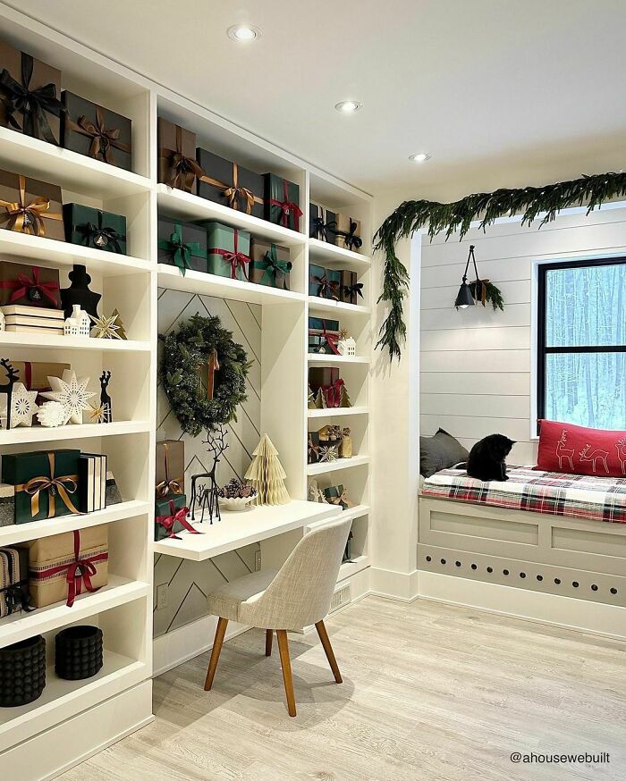 Cozy room with festive Christmas-decorating-ideas, featuring wreaths, gifts, and a window seat with plaid cushions.