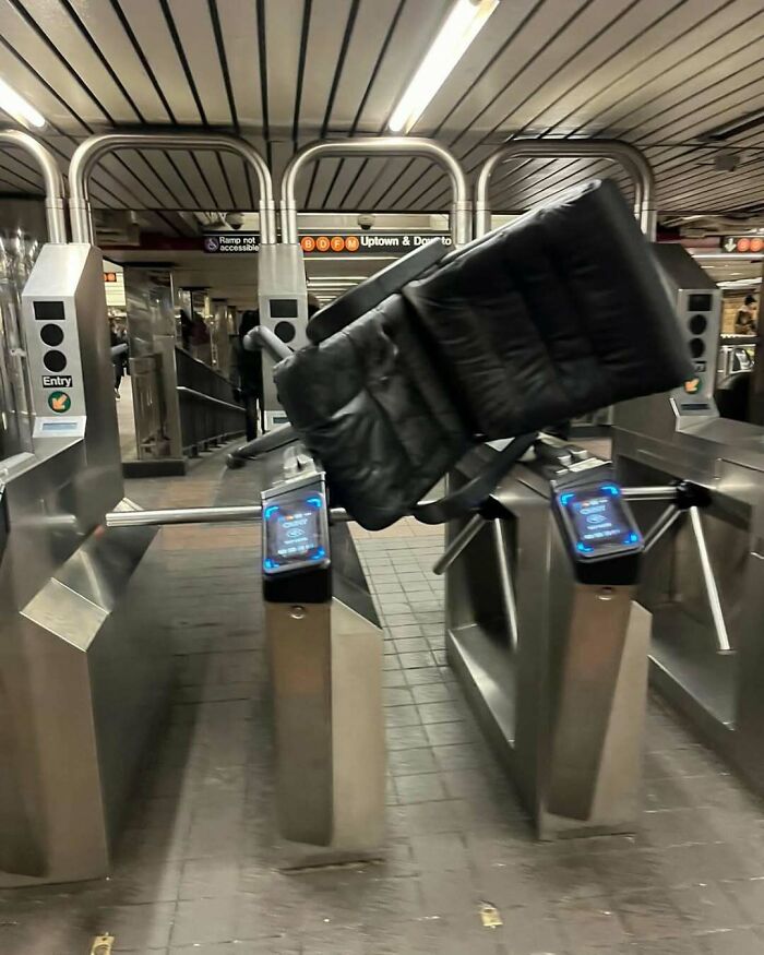 Couch awkwardly stuck in New York subway turnstile, capturing a humorous scene.