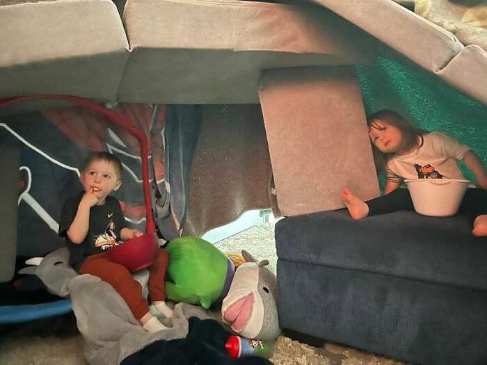 Kids enjoying a creative couch cushion fort indoors, showcasing parenting genius tricks.