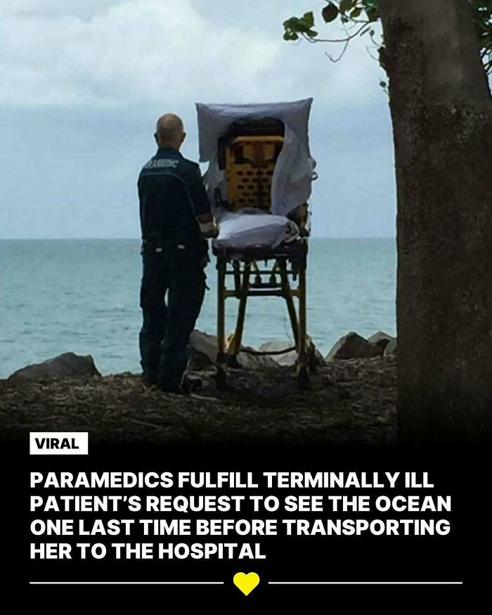 Paramedic stands by stretcher facing the ocean, fulfilling patient's last wish. Wholesome kindness captured by the sea.