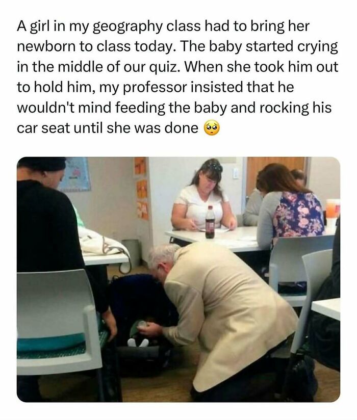 Professor kneeling to care for crying baby in class, exemplifying wholesome kindness amidst students during a quiz.