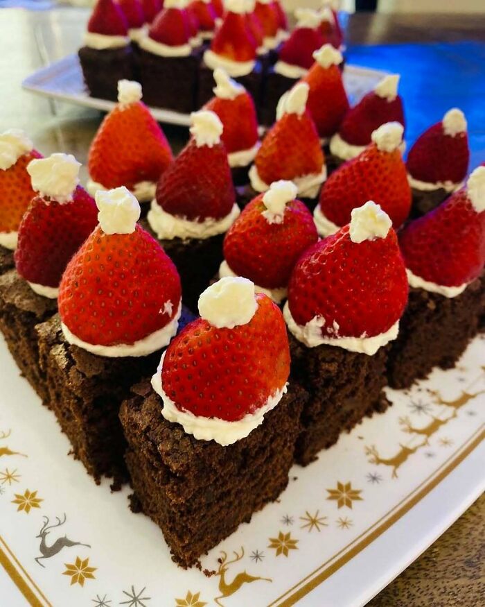 Brownies topped with strawberries and cream resembling Santa hats, perfect for festive Christmas snack ideas.