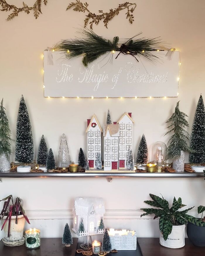 Christmas decorating ideas featuring miniature trees, village houses, and candlelight for a cozy holiday mantel display.