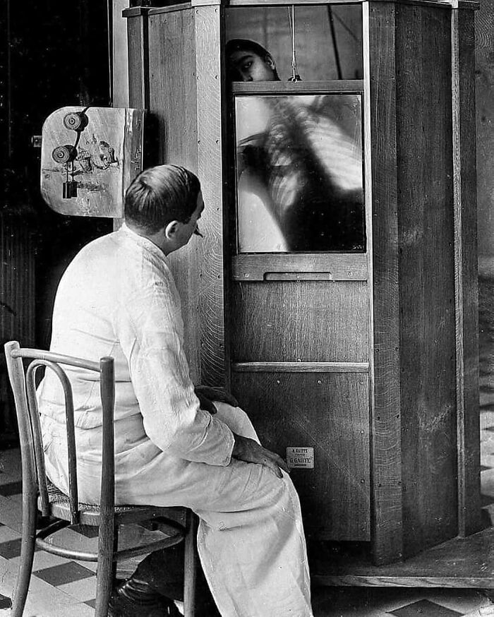 Man examining early X-ray machine, showcasing historical medical technology.