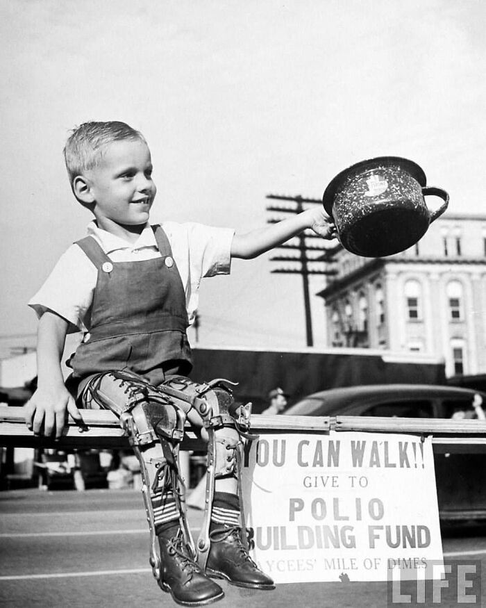 A young boy with leg braces smiling, holding a pot for donations to the polio building fund, illustrating historical resilience.