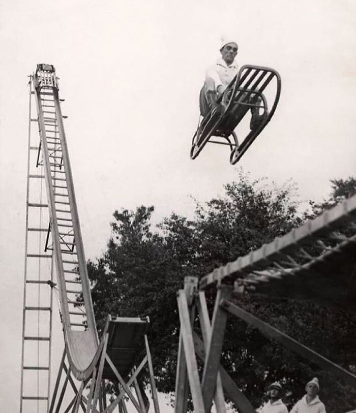 Man on a sled mid-air, demonstrating a historical stunt from an early amusement ride, highlighting lessons from the past.