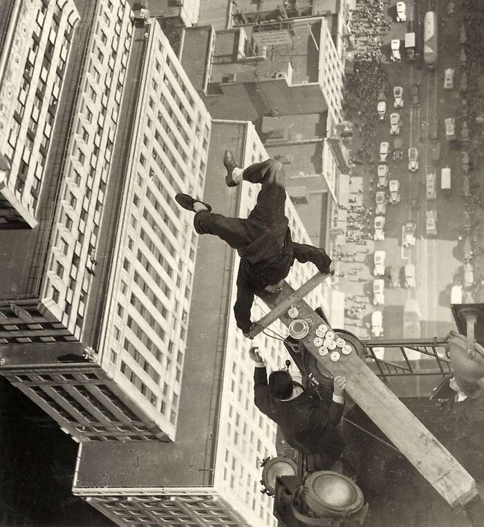 Man performing acrobatics on a skyscraper beam, illustrating historical daredevil stunts in urban settings.