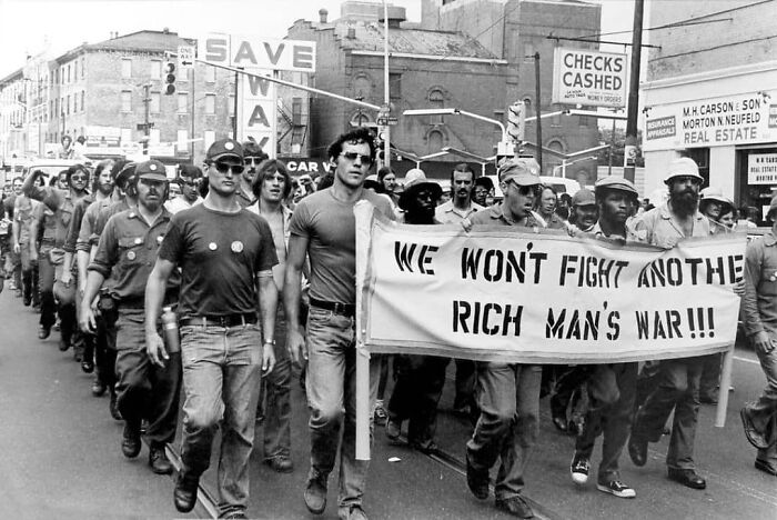 Protesters marching with a banner reading "We Won't Fight Another Rich Man's War," highlighting a historical moment.