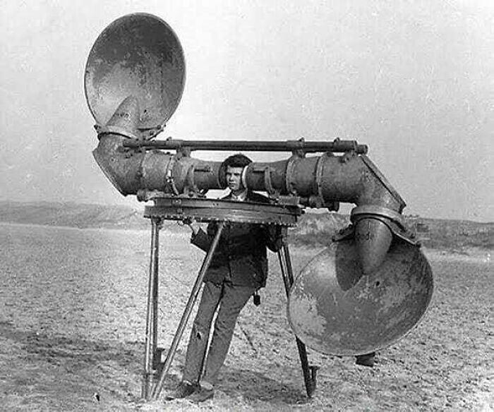 A person with a vintage acoustic listening device, capturing a historical moment.