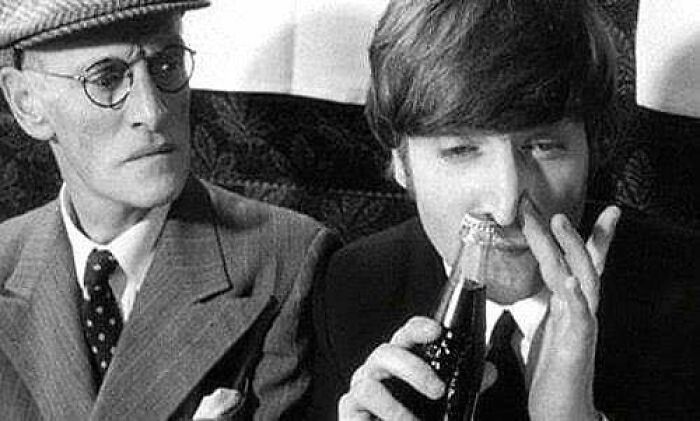 Vintage photo of a young man with a drink bottle to his nose, observed by an older man, illustrating learn from the past.