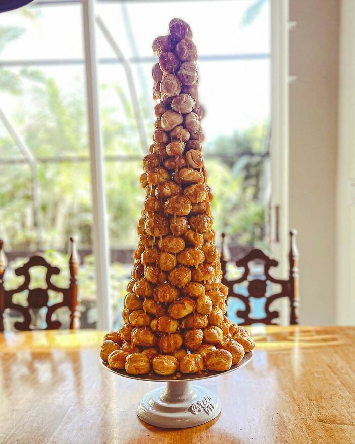 Tower of cream puffs arranged as a festive Christmas snack food idea on a dining table.