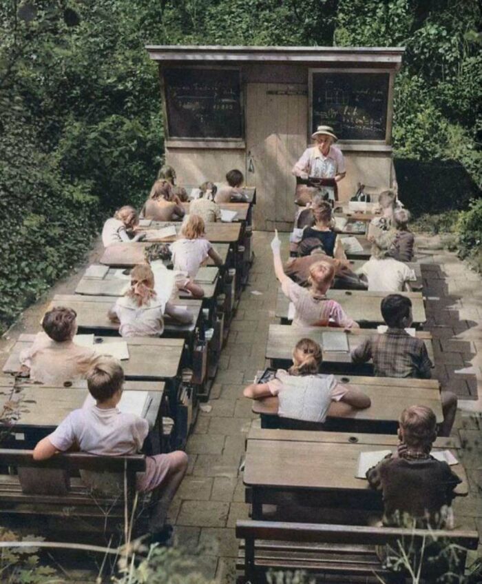 Outdoor classroom with kids sitting at desks, teacher in front; a glimpse of interesting history.