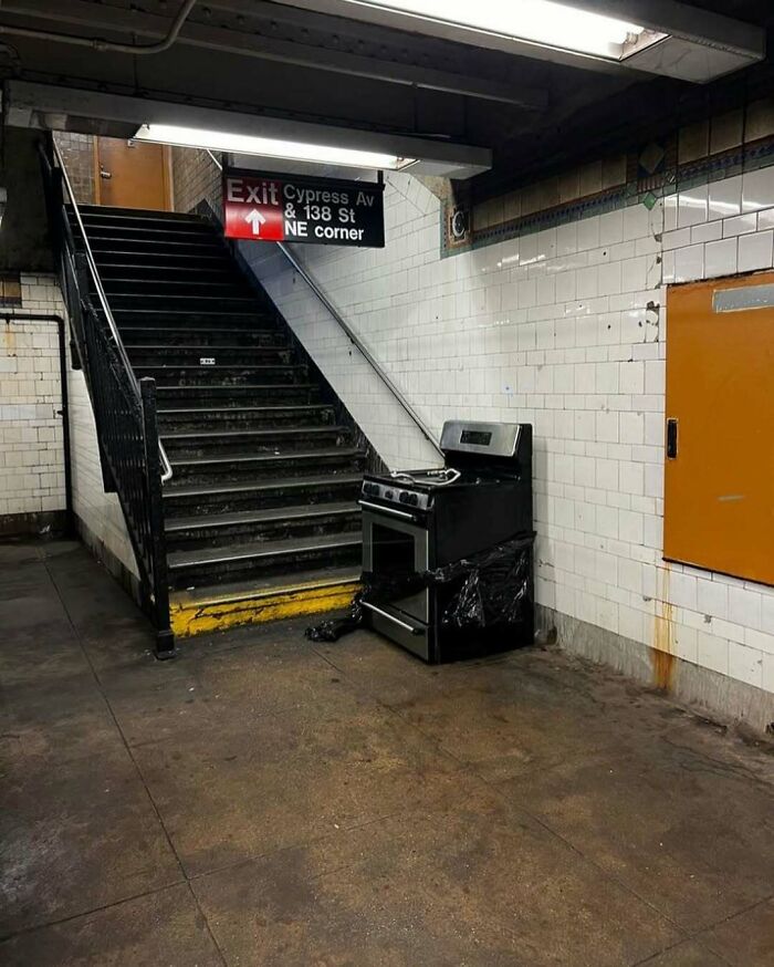 Stove placed humorously in a New York subway station near stairs.