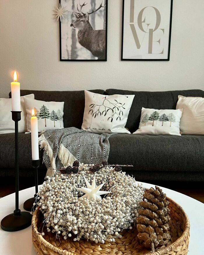 Cozy living room with Christmas-decorating-ideas, featuring a wreath, pinecones, candles, and festive pillows.