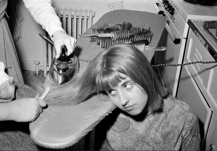 Woman ironing hair on an ironing board, illustrating historical beauty practices.