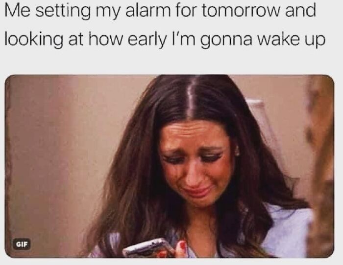 Woman looking upset while setting an early alarm, a relatable work meme to share with colleagues.