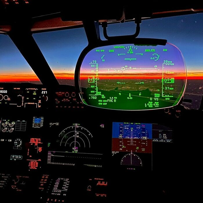 Aircraft cockpit view at sunset with HUD display, resembling videogame graphics.