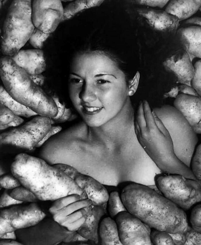 Woman surrounded by potatoes in a vintage black and white photo, highlighting interesting history facts.