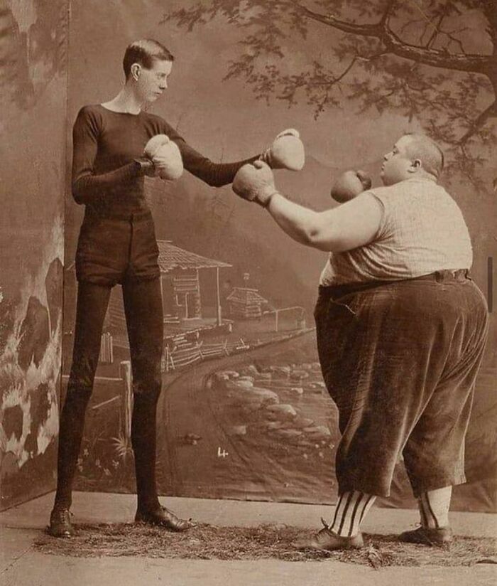 Two boxers, one tall and slim, the other short and stout, posing in vintage gloves, illustrating interesting history facts.