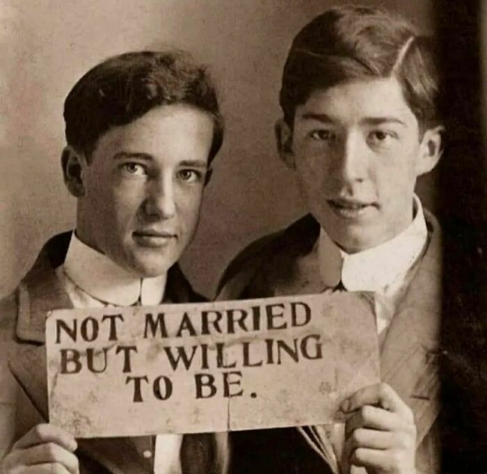 Two historical young men holding a sign reading "Not married but willing to be," showcasing an interesting history pic.