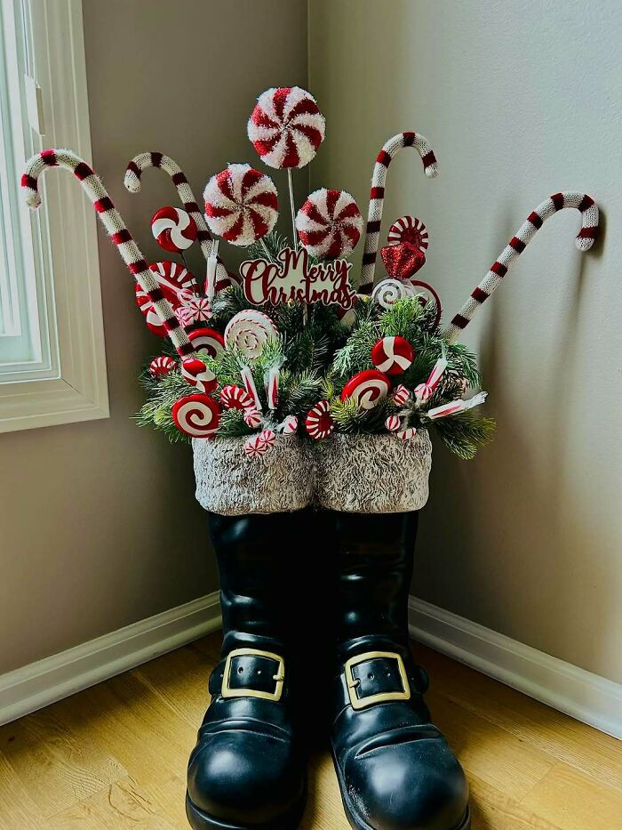 Christmas-decorating-ideas featuring Santa boots filled with festive candy canes and greenery arrangement.