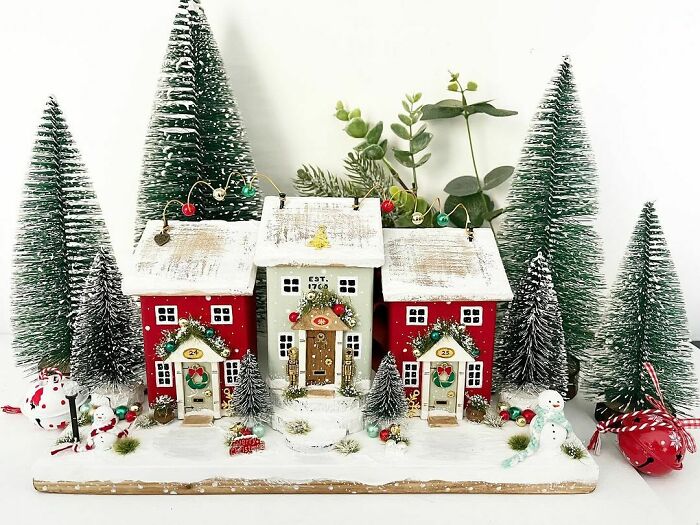 Miniature winter village with snow-covered houses and pine trees for Christmas decorating ideas.