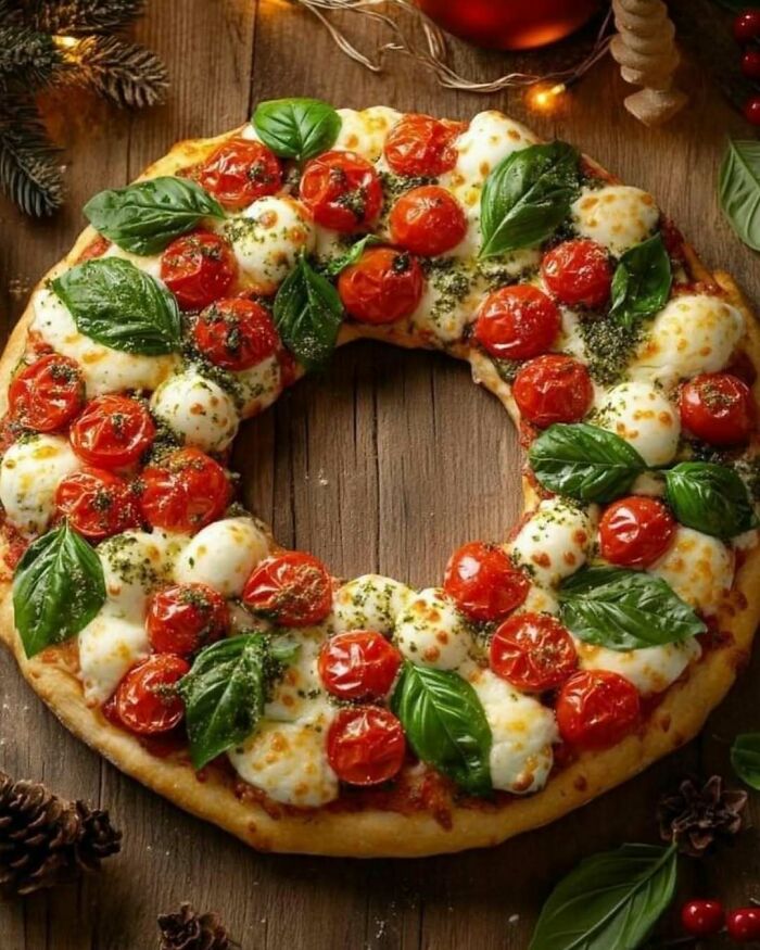 Christmas snack wreath pizza with tomatoes, mozzarella, and basil on a wooden table.