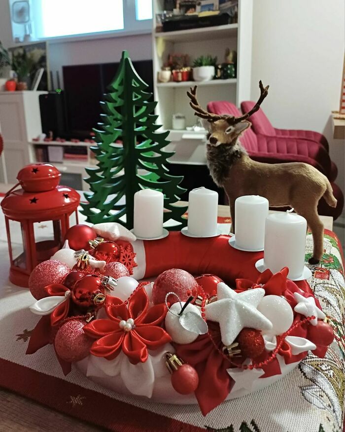 Christmas decorating idea featuring a festive wreath with candles, ornaments, reindeer figurine, and a decorative tree.